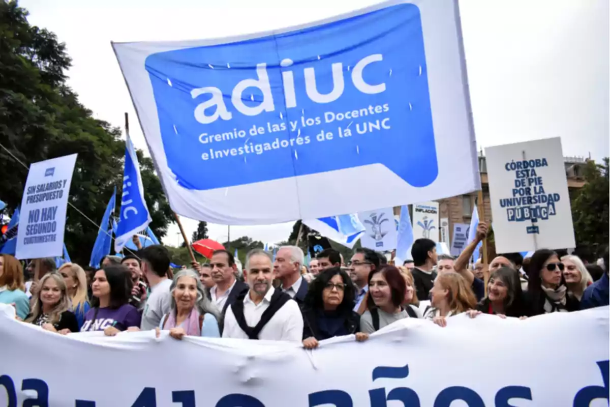 People marching in a demonstration with signs and flags in support of public universities and the rights of teachers and researchers