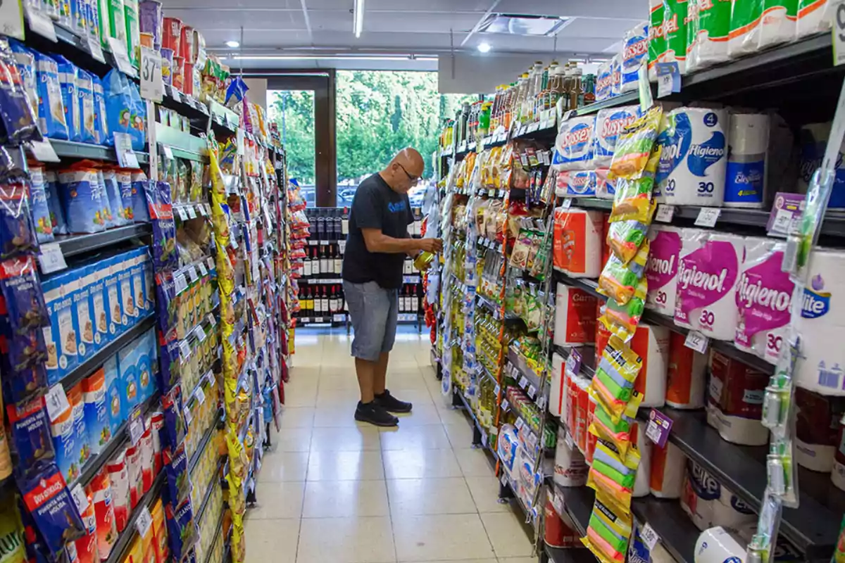Man shopping in a supermarket aisle surrounded by shelves filled with a variety of products