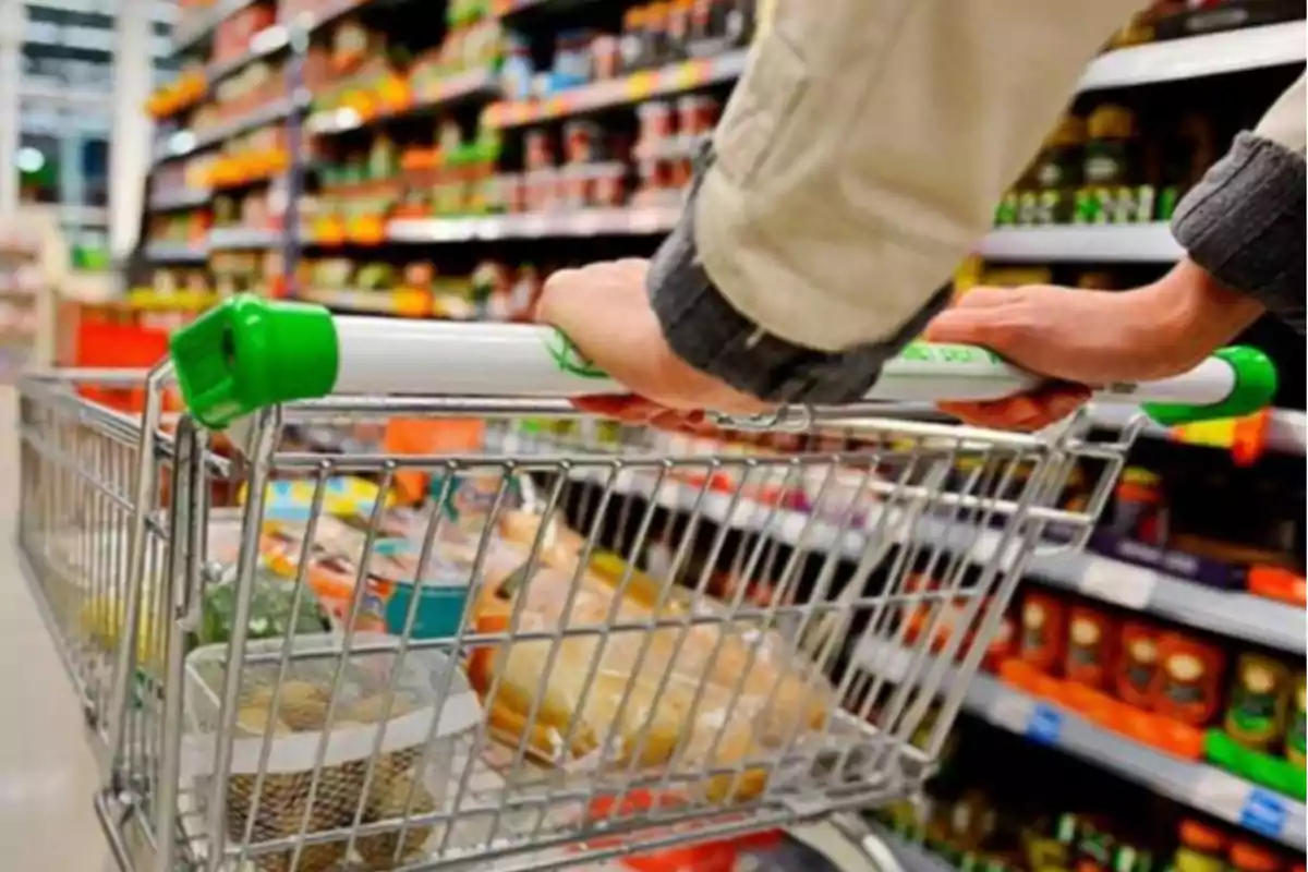 Person pushing a shopping cart full of products down a store aisle Person pushing a shopping cart full of products down a store aisle