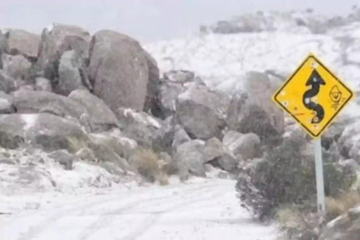 Snow-covered path with large rocks and dangerous curves road sign Snow-covered path with large rocks and dangerous curves road sign
