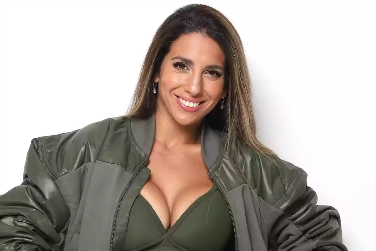 Mujer sonriendo con chaqueta verde y top a juego sobre fondo blanco