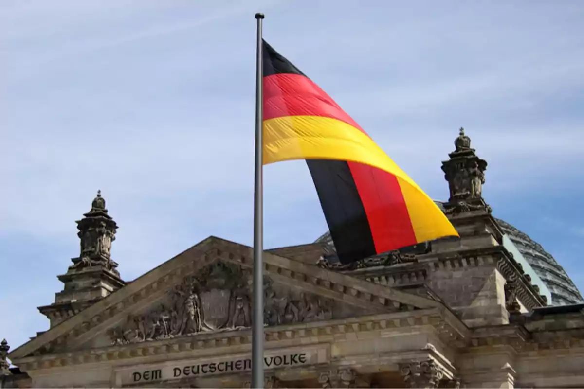 Bandera de Alemania ondeando frente a un edificio histórico Bandera de Alemania ondeando frente a un edificio histórico