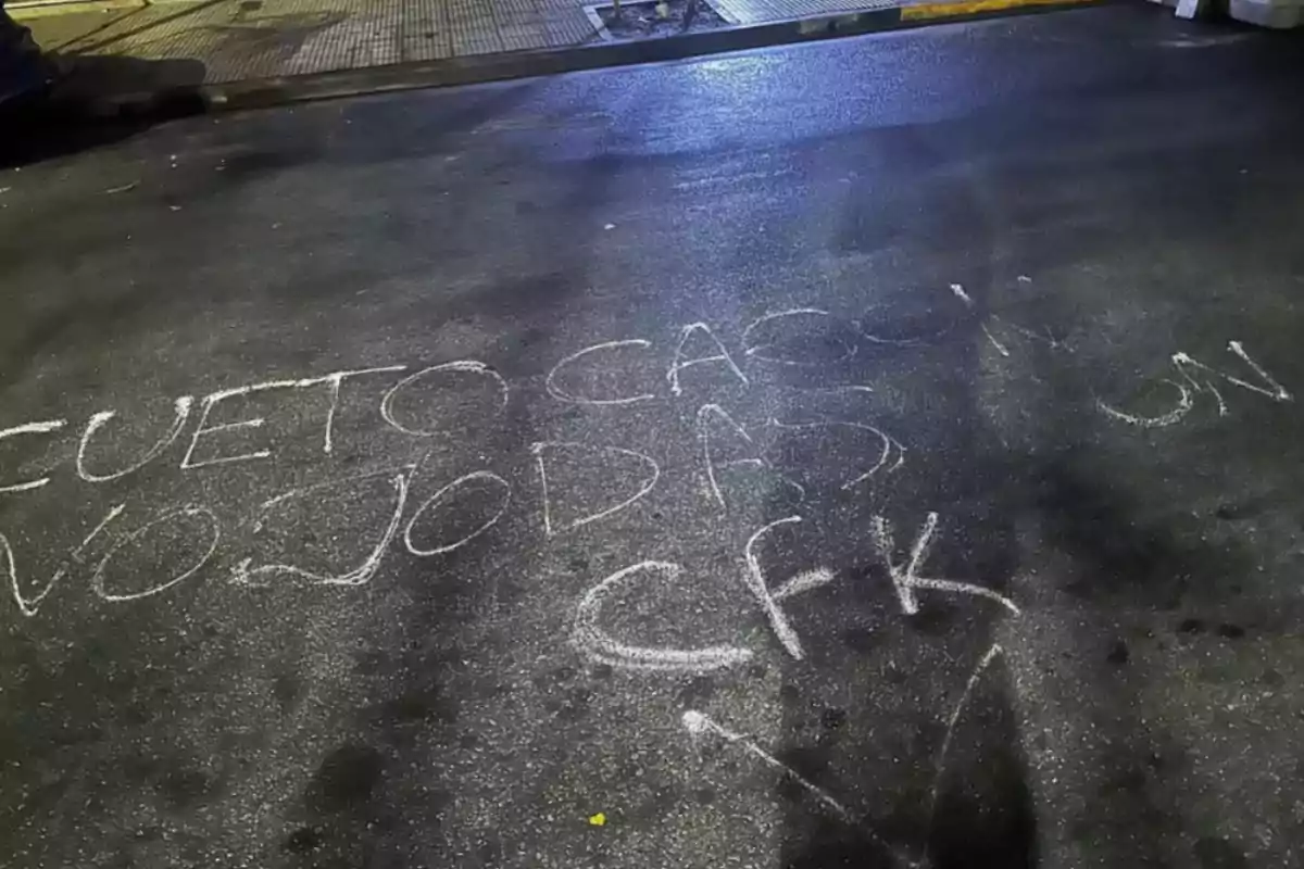 Mensaje escrito con tiza blanca en el asfalto de una calle durante la noche Mensaje escrito con tiza blanca en el asfalto de una calle durante la noche