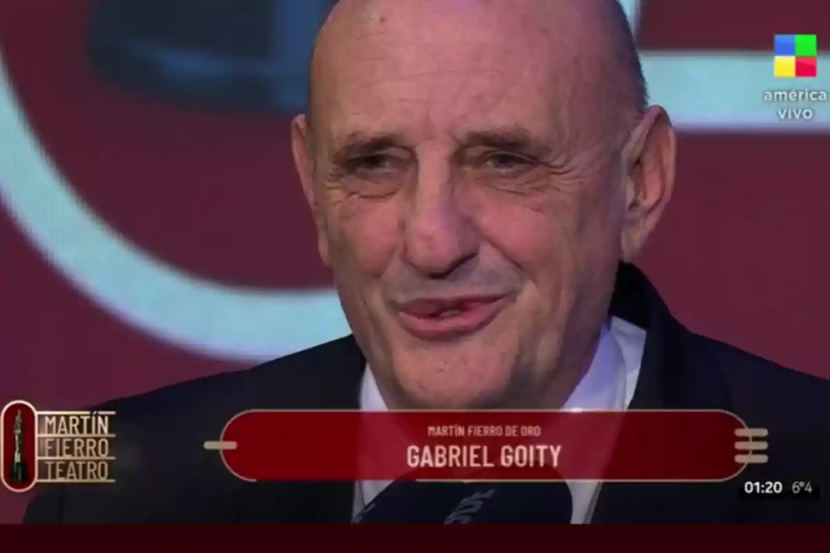 Bald man in a suit receiving the Martín Fierro de Oro award during a live television broadcast Bald man in a suit receiving the Martín Fierro de Oro award during a live television broadcast