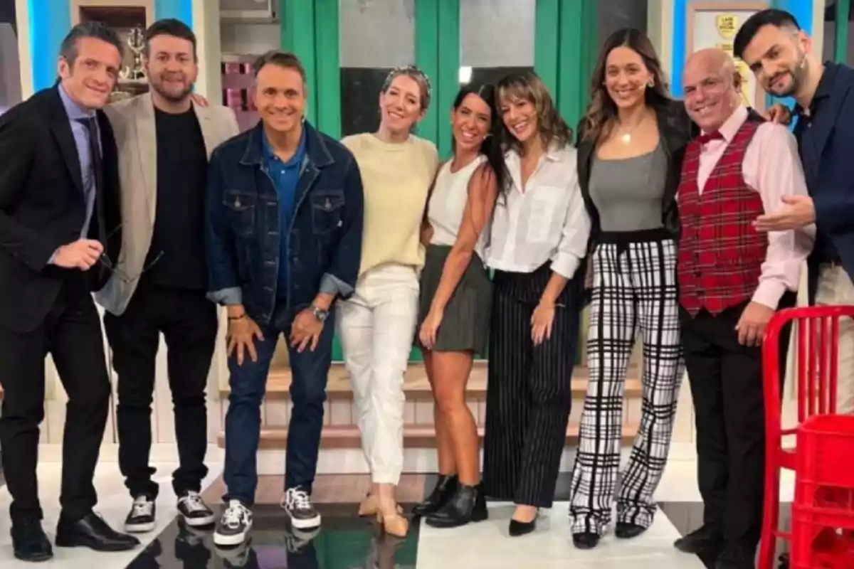 Grupo de personas posando juntas y sonriendo en un estudio de televisión
