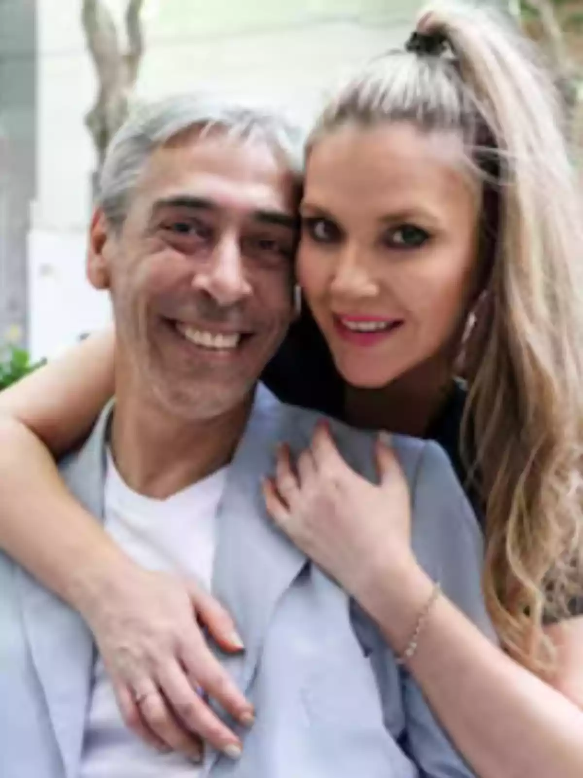 Una pareja sonriente posa abrazada al aire libre