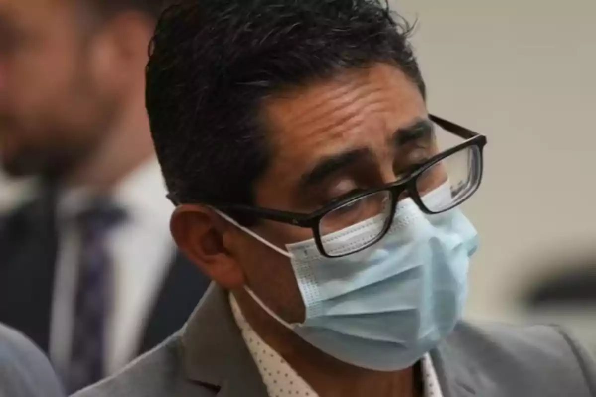 Hombre con gafas y cubrebocas azul claro en un entorno formal Hombre con gafas y cubrebocas azul claro en un entorno formal