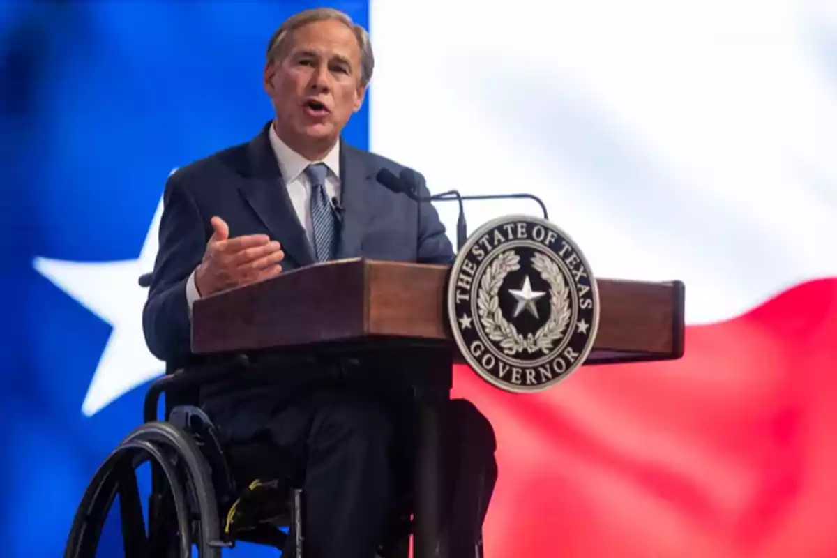 A man in a wheelchair gives a speech at a podium with the Texas governor's seal and the Texas flag in the background. A man in a wheelchair gives a speech at a podium with the Texas governor's seal and the Texas flag in the background.
