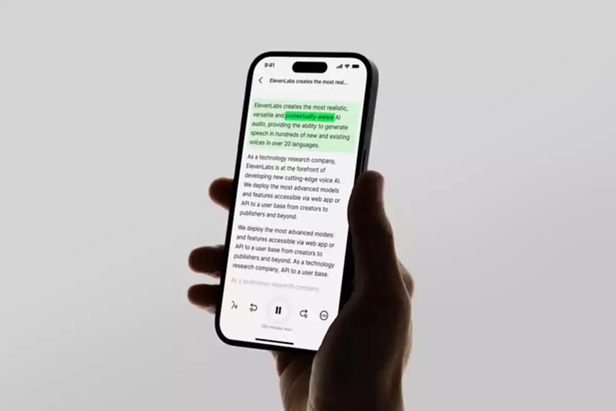 Persona sosteniendo un teléfono inteligente que muestra un texto resaltado en verde en la pantalla sobre un fondo gris claro.