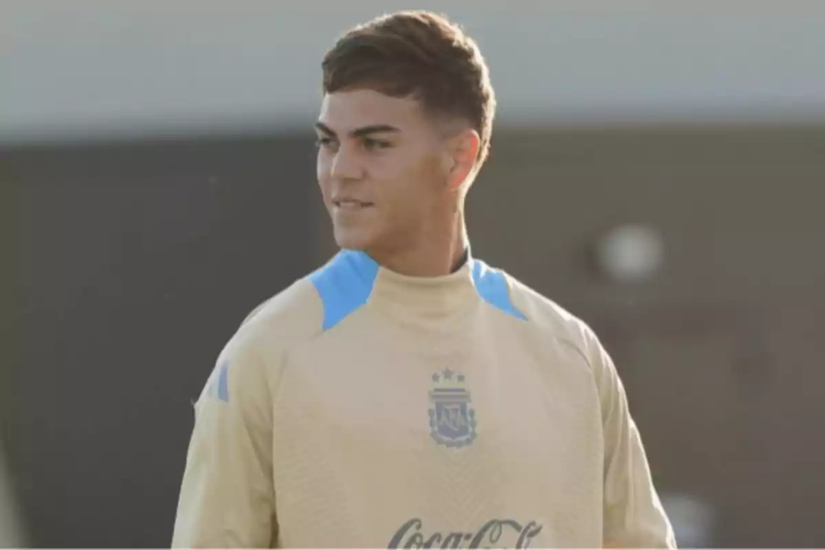 Young player wearing a beige training uniform with light blue details on a sports field Young player wearing a beige training uniform with light blue details on a sports field