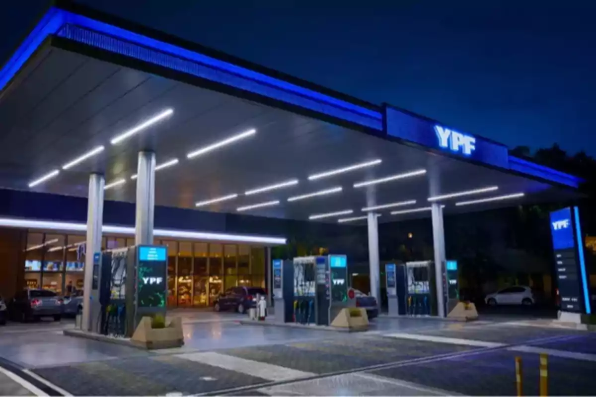YPF gas station lit up at night with pumps and parked cars