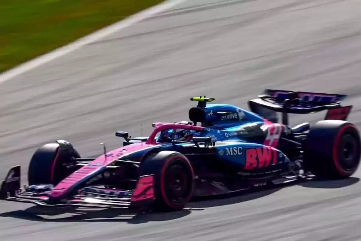 Blue and pink Formula 1 car racing at high speed on a track Blue and pink Formula 1 car racing at high speed on a track