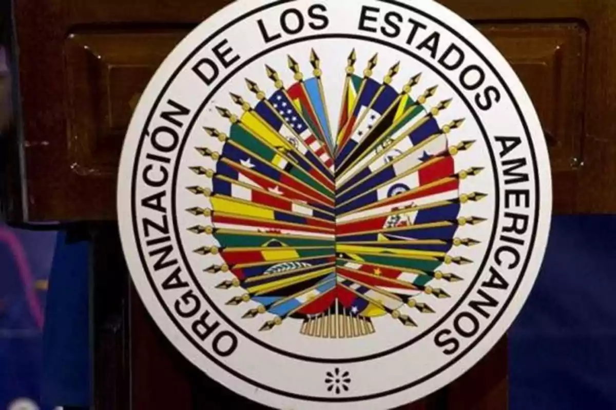 Escudo de la Organización de los Estados Americanos con varias banderas de países miembros en el centro