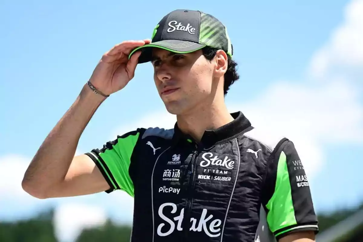Auto racing driver in a black and green team uniform, wearing a cap and looking toward the horizon on a sunny day Auto racing driver in a black and green team uniform, wearing a cap and looking toward the horizon on a sunny day