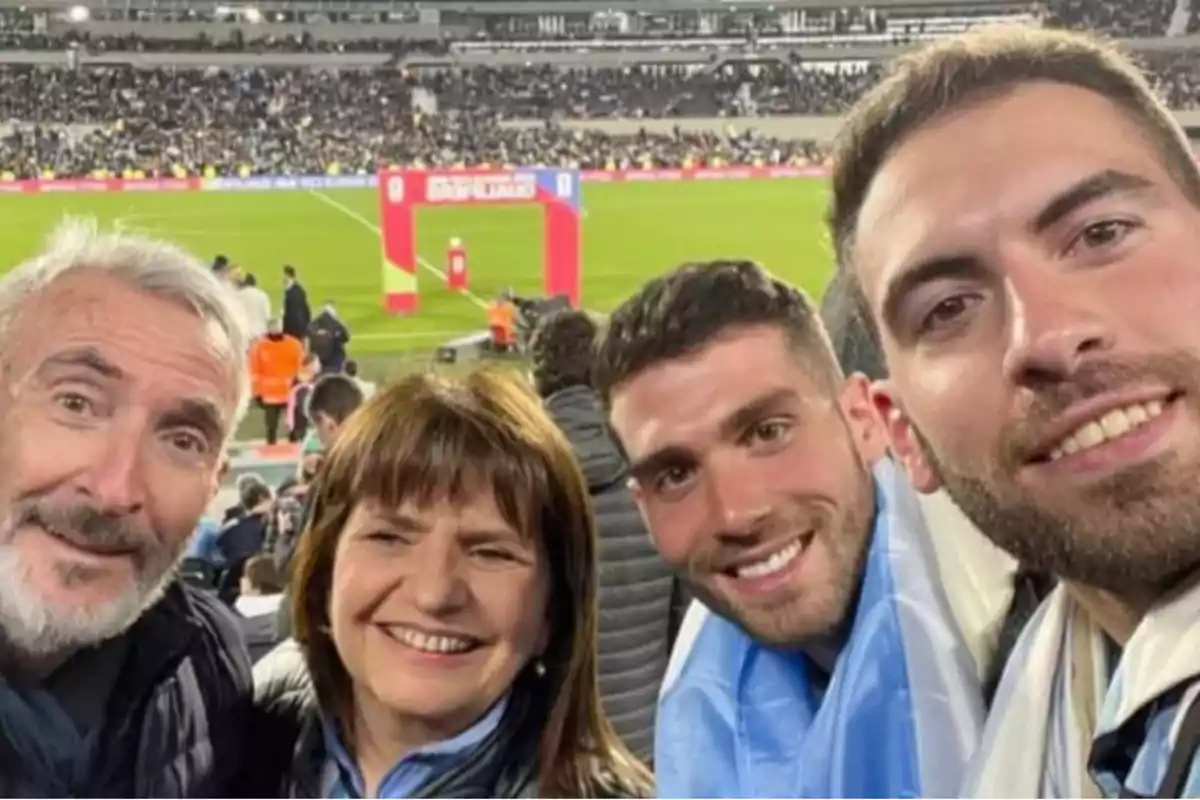 Cuatro personas sonríen mientras se toman una selfie en un estadio de fútbol lleno de público. Cuatro personas sonríen mientras se toman una selfie en un estadio de fútbol lleno de público.
