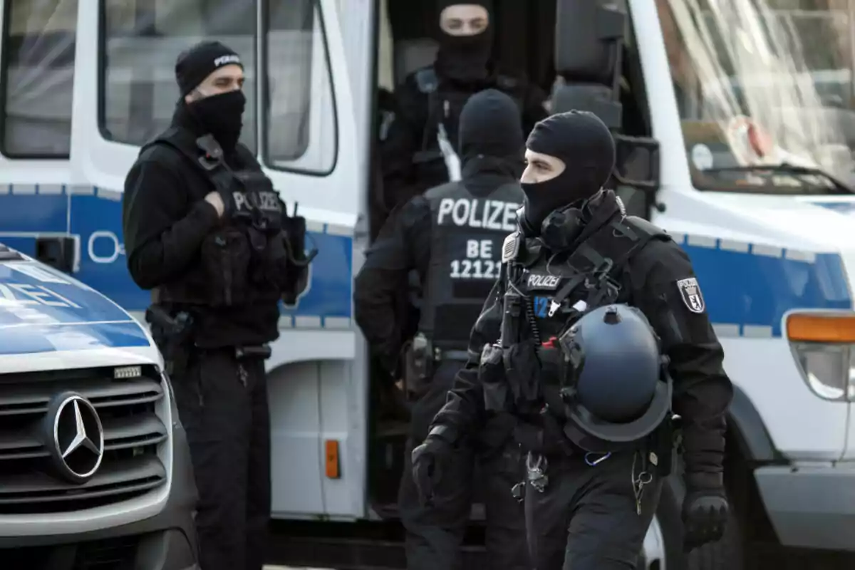 Policías alemanes fuertemente armados y con equipo táctico se preparan junto a vehículos policiales