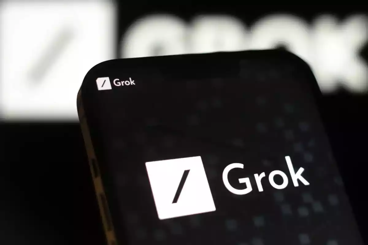 Pantalla de un teléfono móvil mostrando el logotipo y nombre de la aplicación Grok en primer plano, con el mismo logotipo desenfocado en el fondo. Pantalla de un teléfono móvil mostrando el logotipo y nombre de la aplicación Grok en primer plano, con el mismo logotipo desenfocado en el fondo.