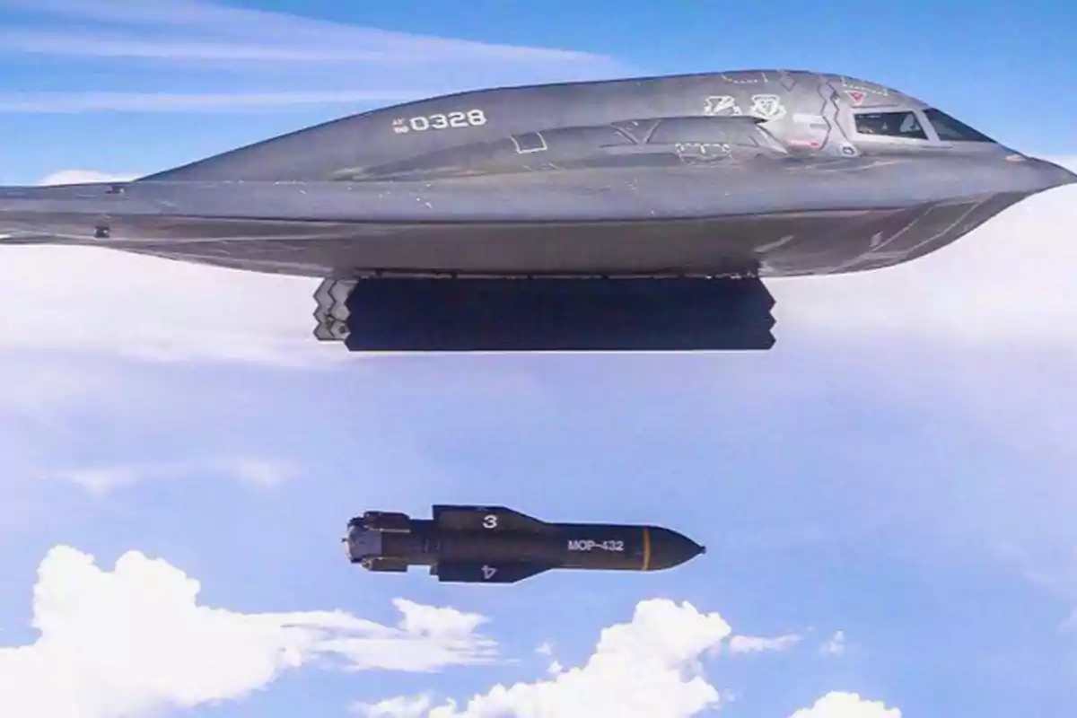 B-2 Spirit military aircraft dropping an MOP-432 bomb in mid-flight over a blue sky with white clouds