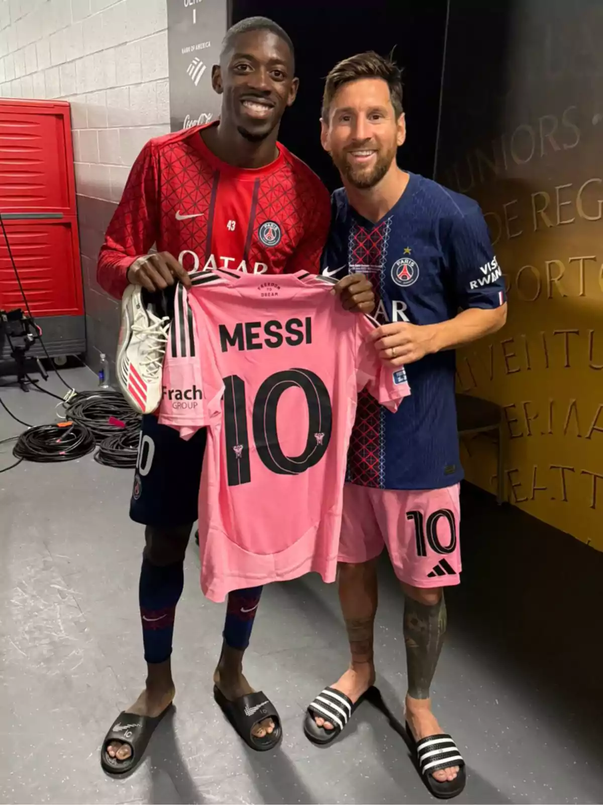 Dos futbolistas sonríen mientras sostienen una camiseta rosa con el nombre Messi y el número 10 Dos futbolistas sonríen mientras sostienen una camiseta rosa con el nombre Messi y el número 10