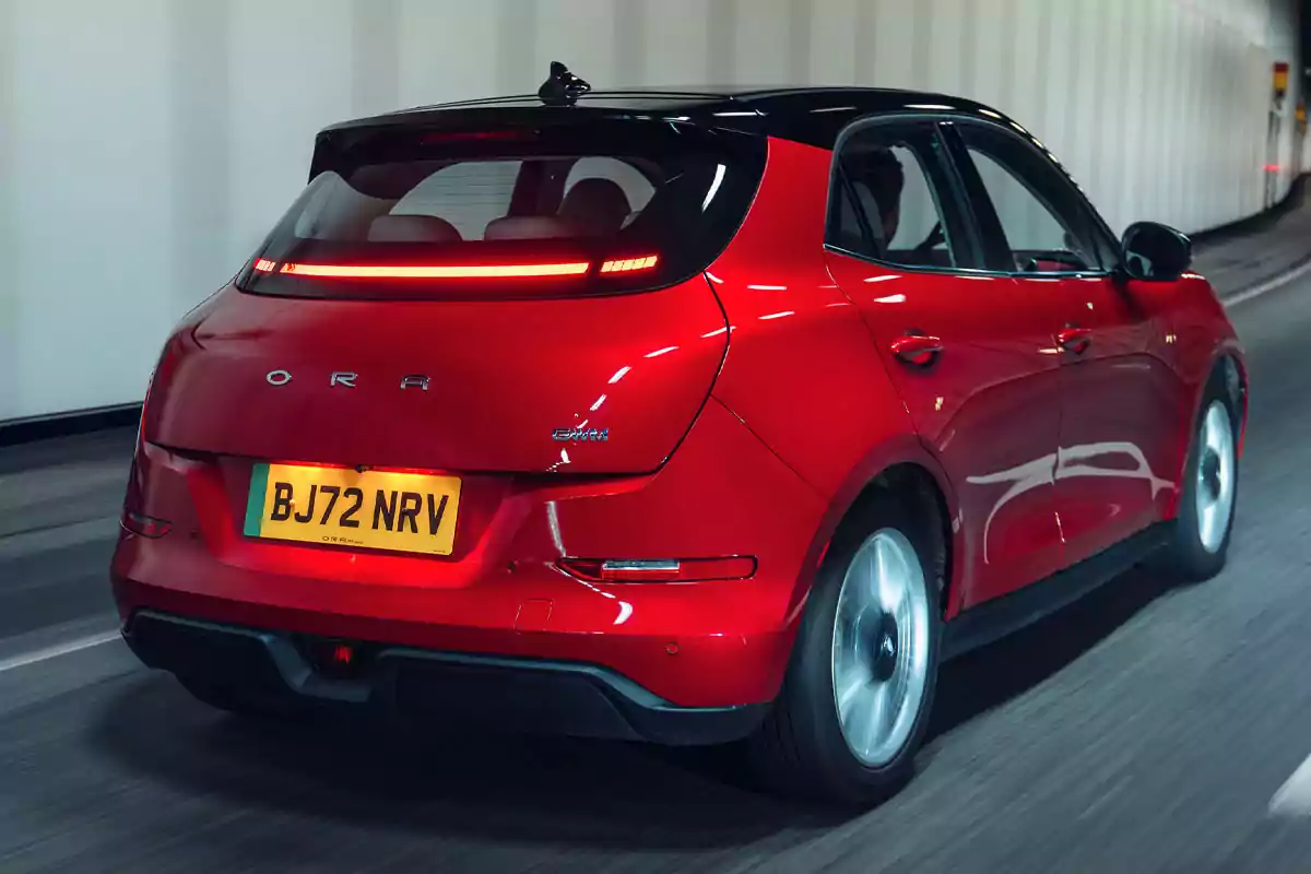 Red electric compact car driving through a tunnel with a yellow UK license plate Red electric compact car driving through a tunnel with a yellow UK license plate
