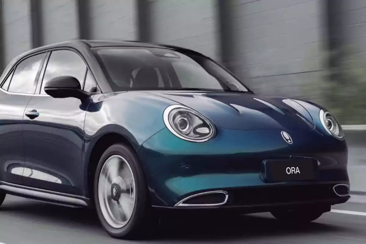 Blue electric compact car driving on a road next to a gray wall Blue electric compact car driving on a road next to a gray wall