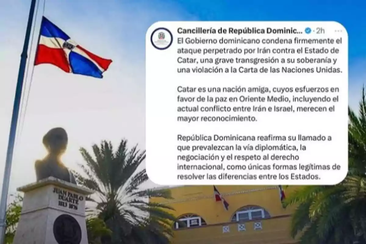 Una bandera de República Dominicana ondea junto a un busto de Juan Pablo Duarte y un edificio amarillo, mientras se muestra un comunicado oficial de la Cancillería dominicana sobre un ataque de Irán a Catar.