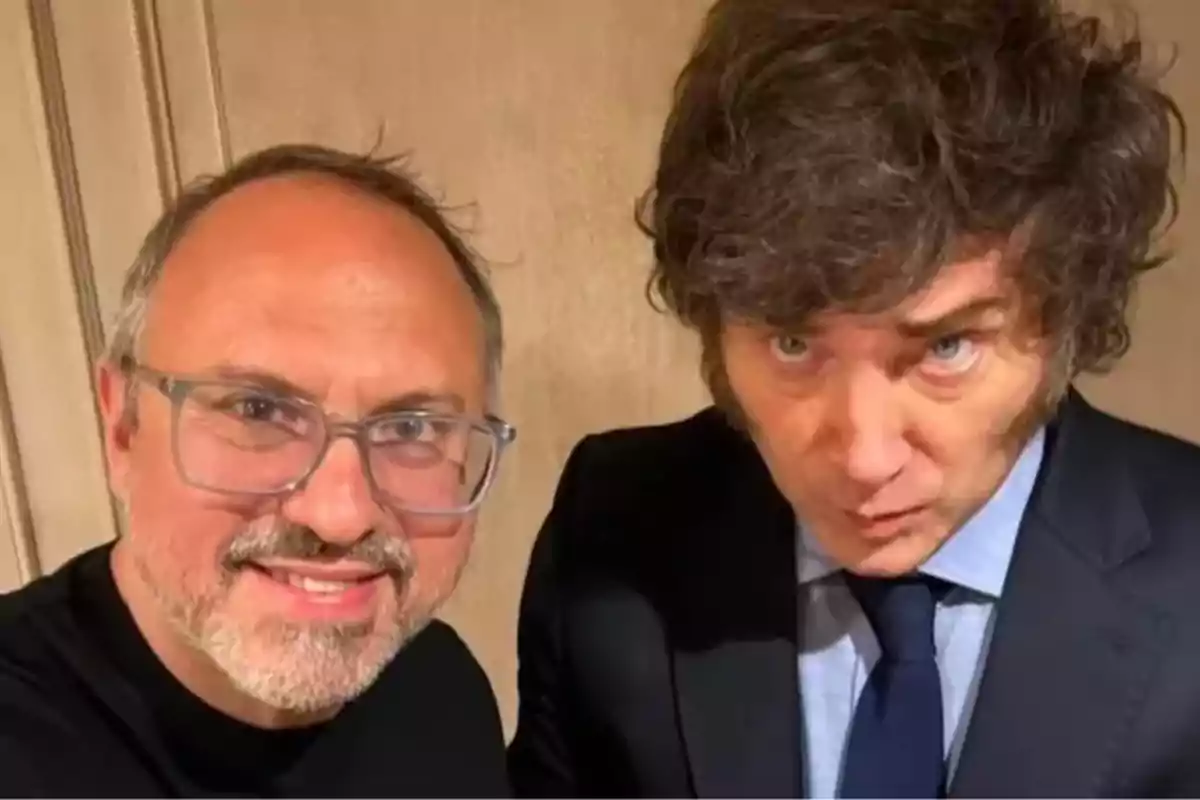 Dos hombres posan juntos para una selfie uno de ellos lleva gafas y barba mientras que el otro viste traje y corbata y tiene el cabello rizado y abundante Dos hombres posan juntos para una selfie uno de ellos lleva gafas y barba mientras que el otro viste traje y corbata y tiene el cabello rizado y abundante