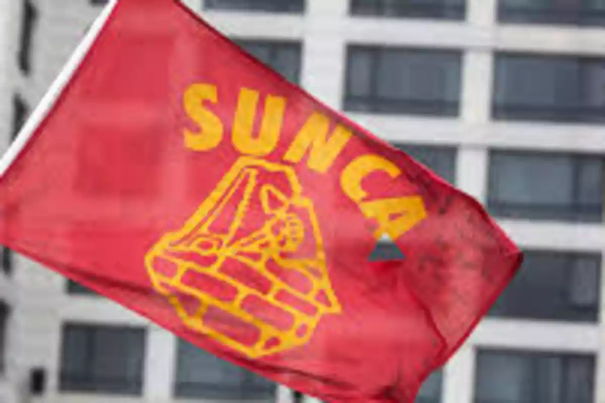 Red flag with the logo and the word SUNCA in yellow waving in front of a building Red flag with the logo and the word SUNCA in yellow waving in front of a building
