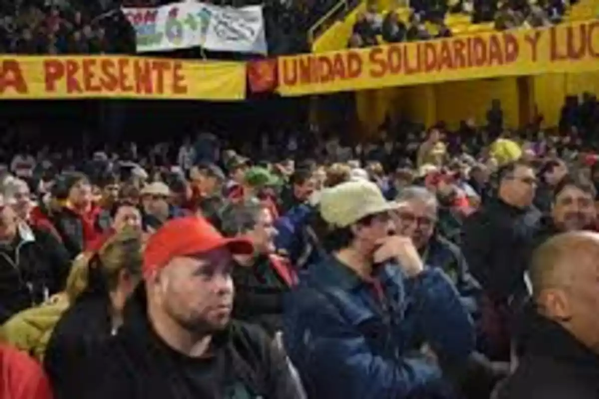 People gathered at an event with yellow and red banners displaying messages of unity and solidarity People gathered at an event with yellow and red banners displaying messages of unity and solidarity