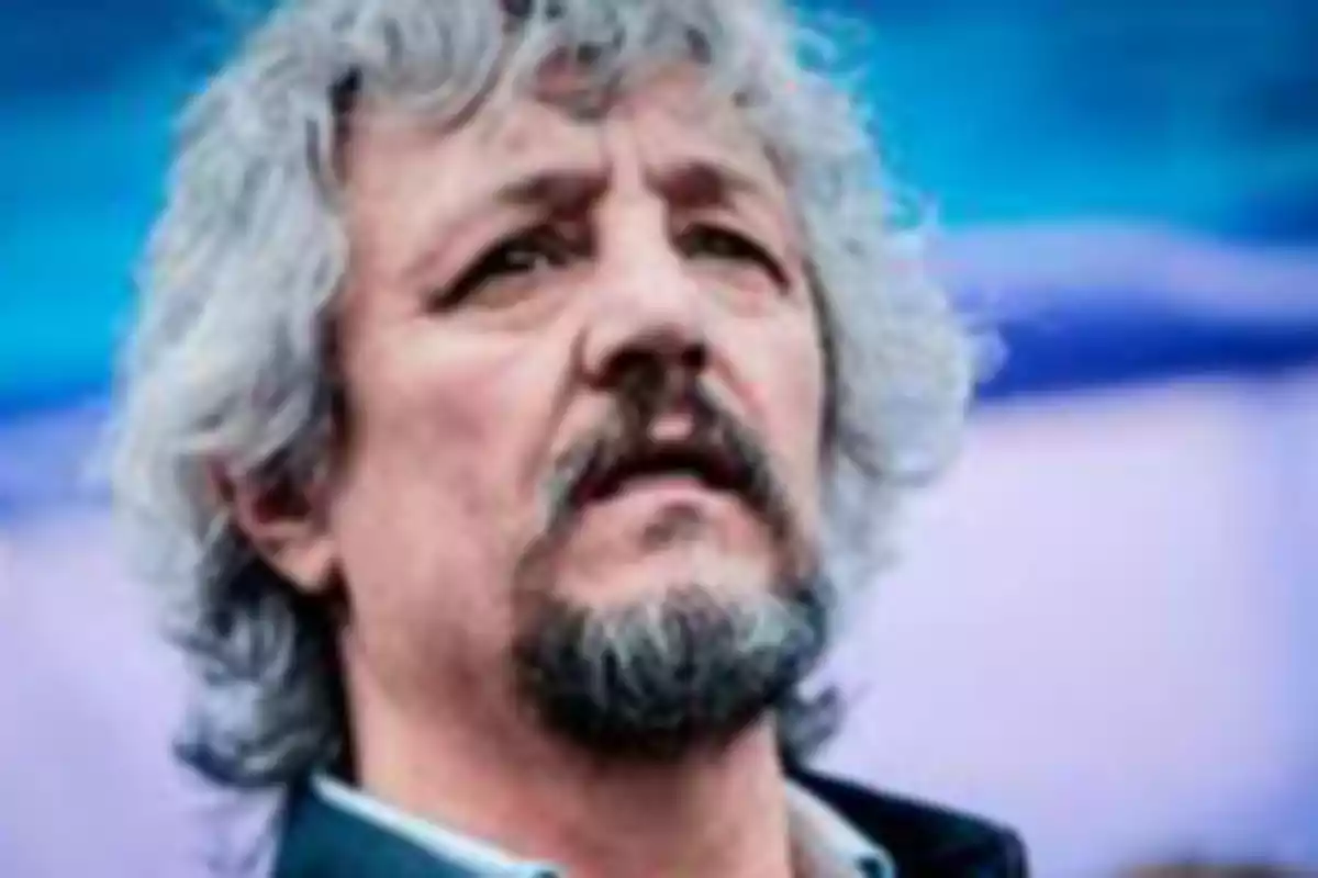 Gray-haired man with a beard looking up with a serious expression and a blurred blue background Gray-haired man with a beard looking up with a serious expression and a blurred blue background