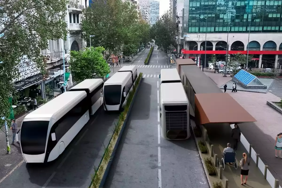 Two modern buses travel along a dedicated lane on an urban avenue with trees and buildings, while people wait at an accessible station.