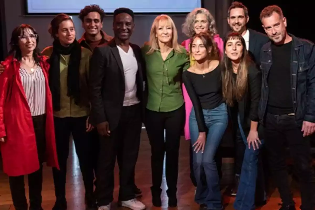 A group of people posing together and smiling in an indoor setting with warm lighting A group of people posing together and smiling in an indoor setting with warm lighting