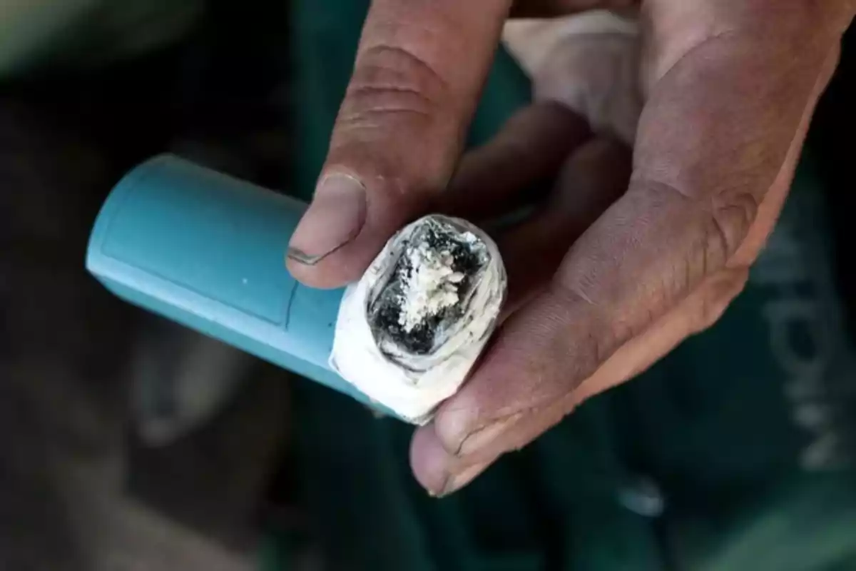 Mano sosteniendo un inhalador azul modificado con una sustancia blanca en la boquilla Mano sosteniendo un inhalador azul modificado con una sustancia blanca en la boquilla