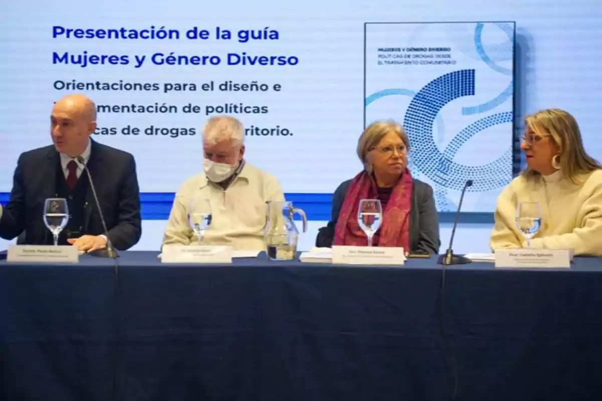 Cuatro personas sentadas en una mesa durante la presentación de una guía sobre mujeres y género diverso con un cartel informativo de fondo Cuatro personas sentadas en una mesa durante la presentación de una guía sobre mujeres y género diverso con un cartel informativo de fondo