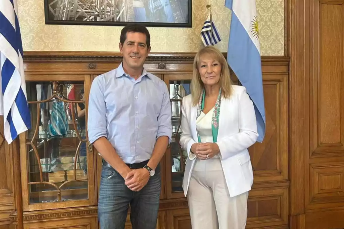 Dos personas posan en una oficina elegante con banderas de Uruguay y Argentina al fondo Dos personas posan en una oficina elegante con banderas de Uruguay y Argentina al fondo