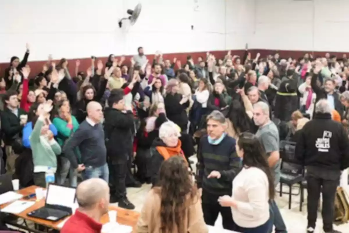A large group of people gathered in a room raising their hands as a sign of voting or participation