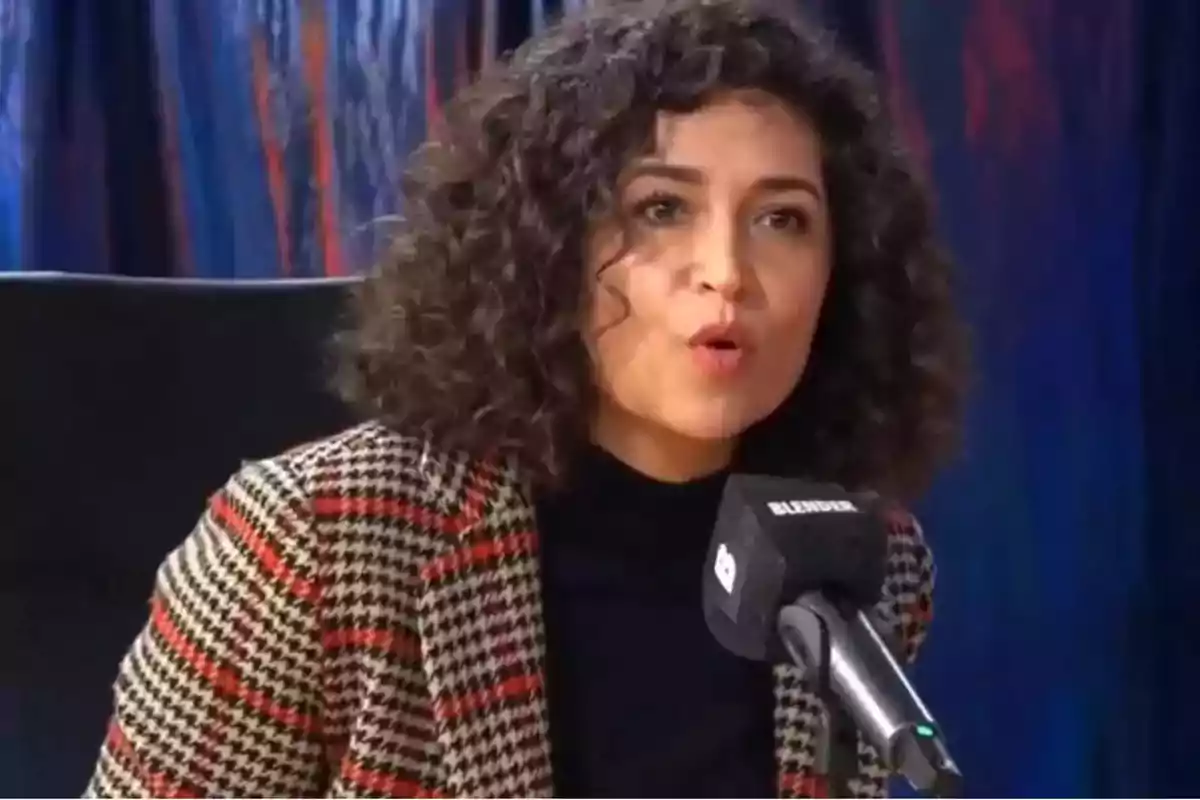 Mujer de cabello rizado hablando frente a un micrófono en un estudio de grabación Mujer de cabello rizado hablando frente a un micrófono en un estudio de grabación