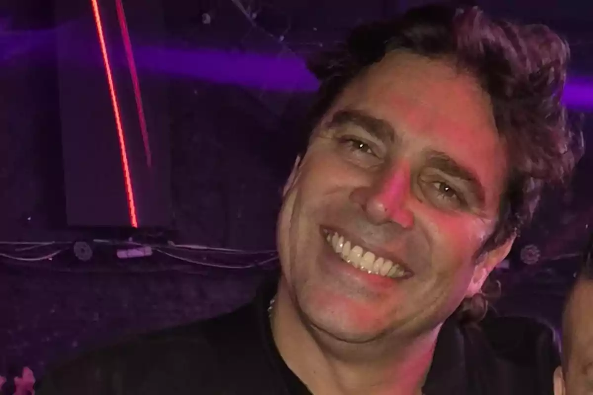 Hombre sonriendo en un ambiente con luces de colores