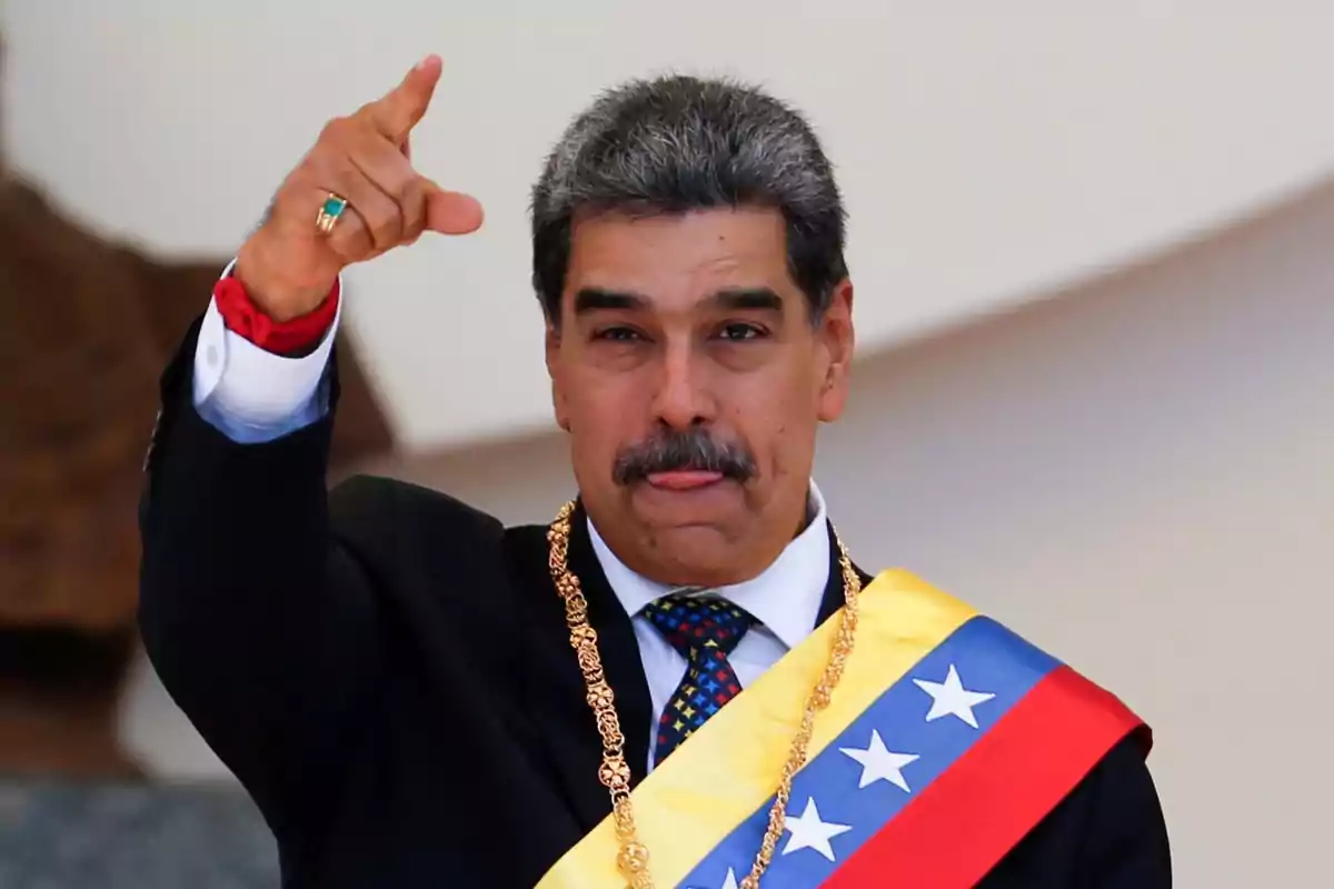 Hombre con bigote vistiendo banda presidencial y cadena dorada levantando la mano y señalando hacia adelante Hombre con bigote vistiendo banda presidencial y cadena dorada levantando la mano y señalando hacia adelante
