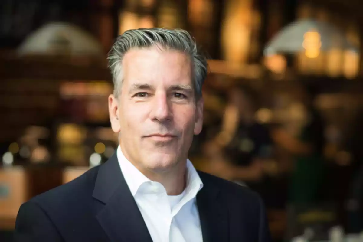 Gray-haired man in a dark suit posing indoors with a blurred background Gray-haired man in a dark suit posing indoors with a blurred background