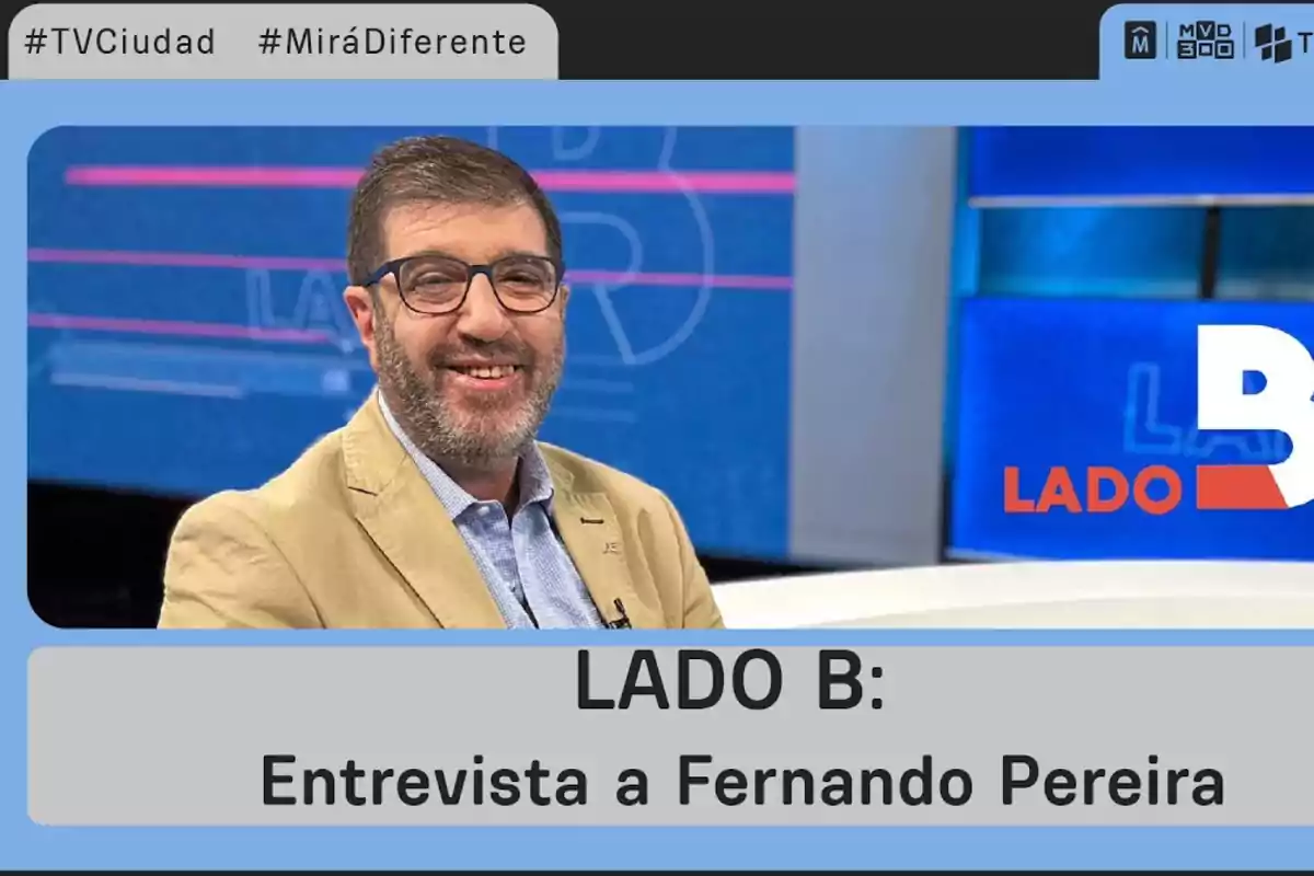 Man with glasses and beige jacket smiles on a TV set with the text LADO B Interview with Fernando Pereira on screen Man with glasses and beige jacket smiles on a TV set with the text LADO B Interview with Fernando Pereira on screen