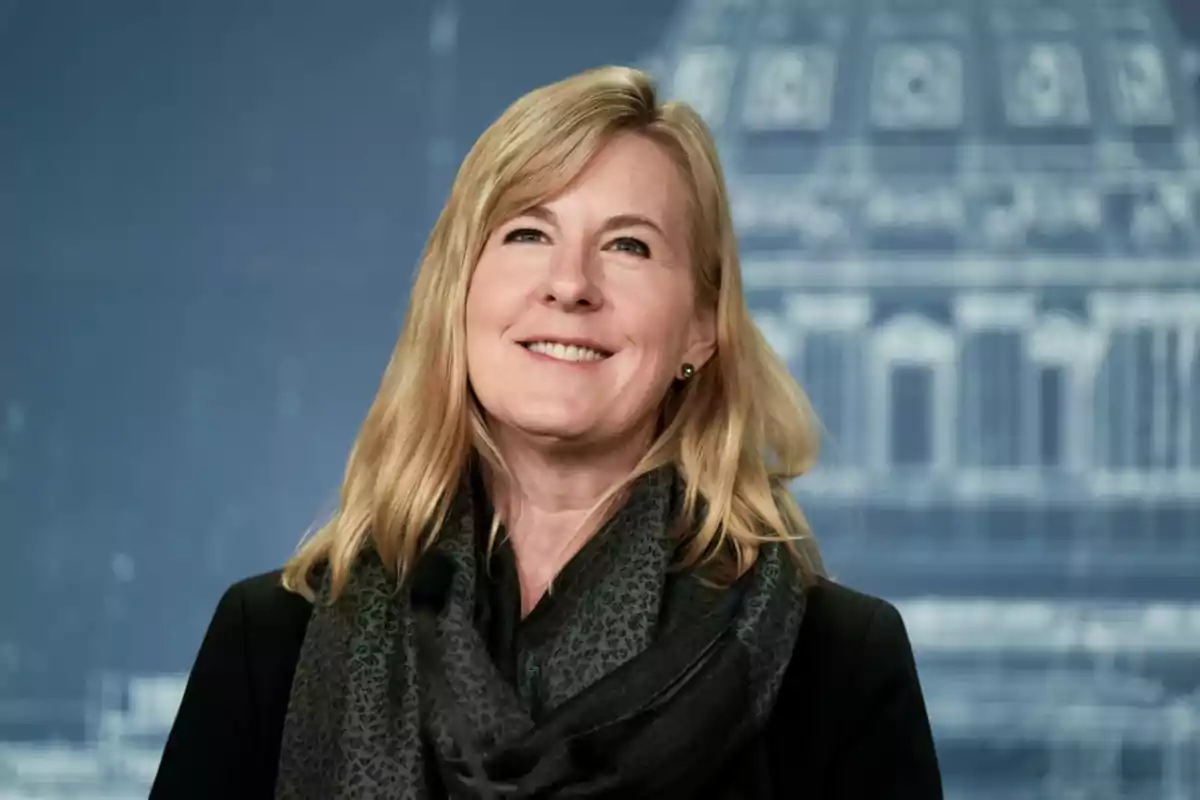 Mujer rubia sonriendo con bufanda oscura y fondo desenfocado de edificio Mujer rubia sonriendo con bufanda oscura y fondo desenfocado de edificio