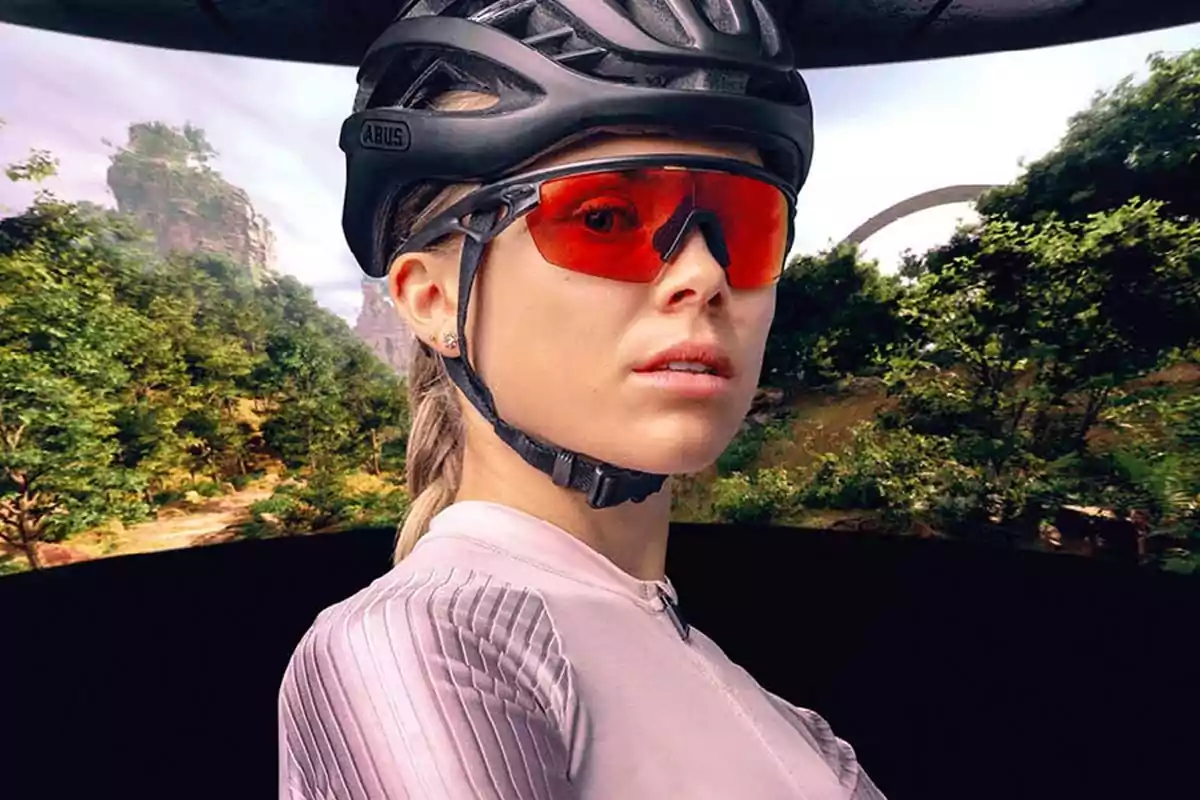 Mujer con casco y gafas deportivas rojas en un entorno natural con árboles y montañas al fondo Mujer con casco y gafas deportivas rojas en un entorno natural con árboles y montañas al fondo
