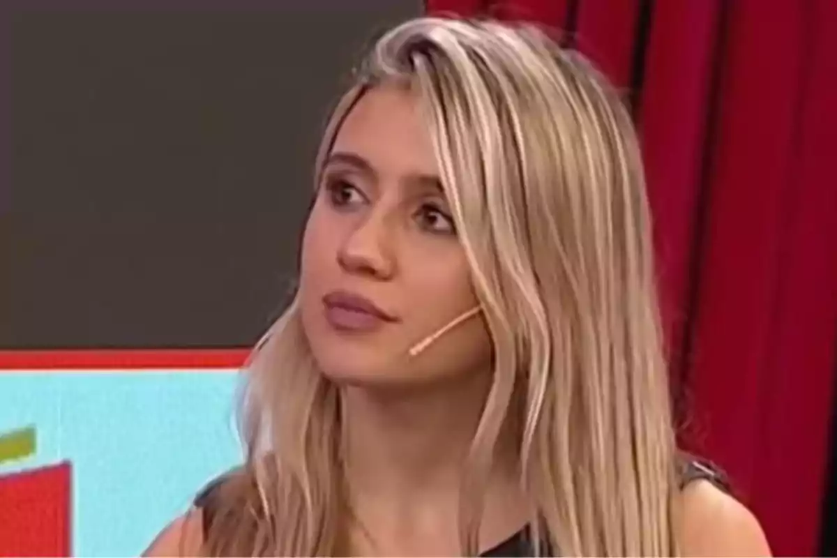 Mujer rubia con micrófono de diadema en un set de televisión con fondo rojo y negro Mujer rubia con micrófono de diadema en un set de televisión con fondo rojo y negro