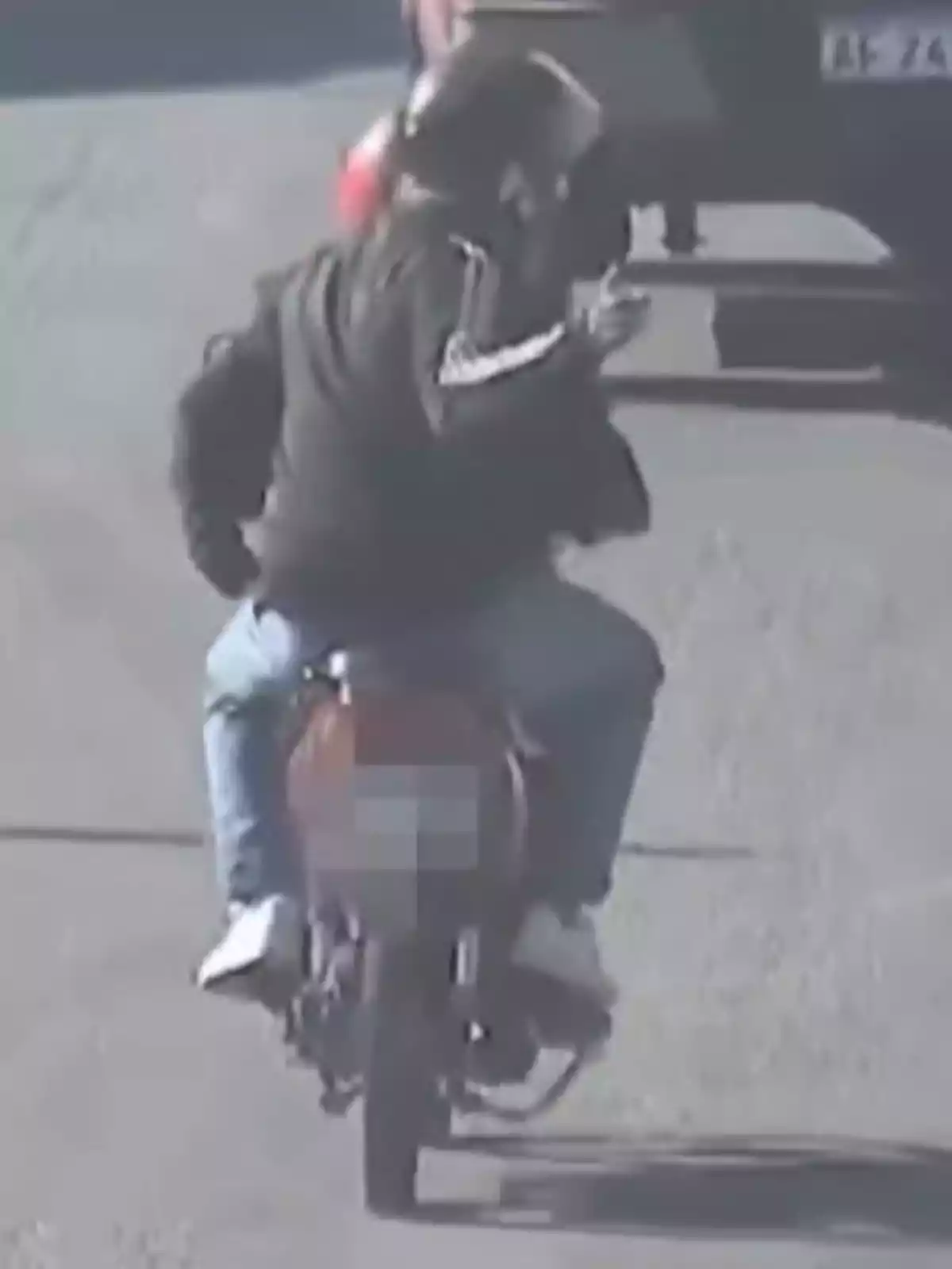 Dos personas con casco viajan en una motocicleta mientras una de ellas parece estar haciendo un gesto con la mano Dos personas con casco viajan en una motocicleta mientras una de ellas parece estar haciendo un gesto con la mano
