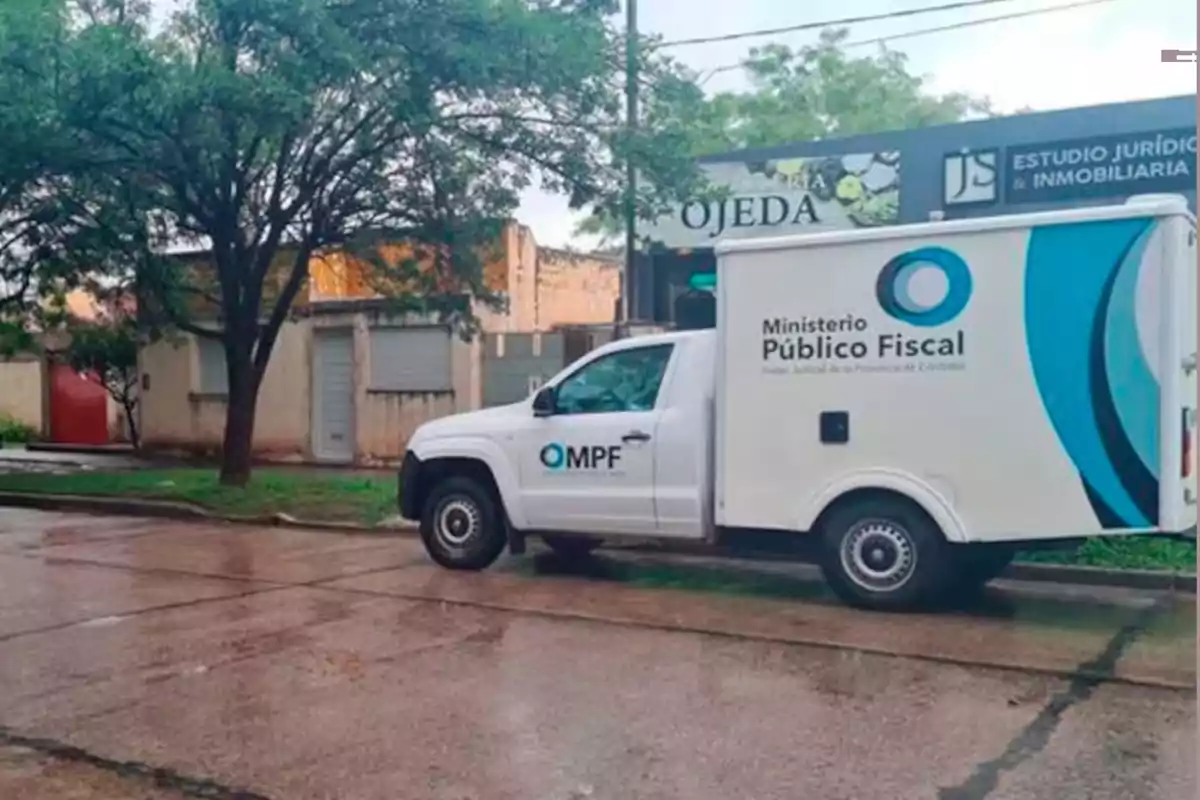 Camioneta blanca del Ministerio Público Fiscal estacionada en una calle mojada frente a un estudio jurídico e inmobiliaria Camioneta blanca del Ministerio Público Fiscal estacionada en una calle mojada frente a un estudio jurídico e inmobiliaria