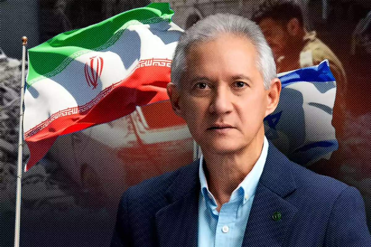 Hombre de cabello canoso con saco azul posando frente a las banderas de Irán e Israel