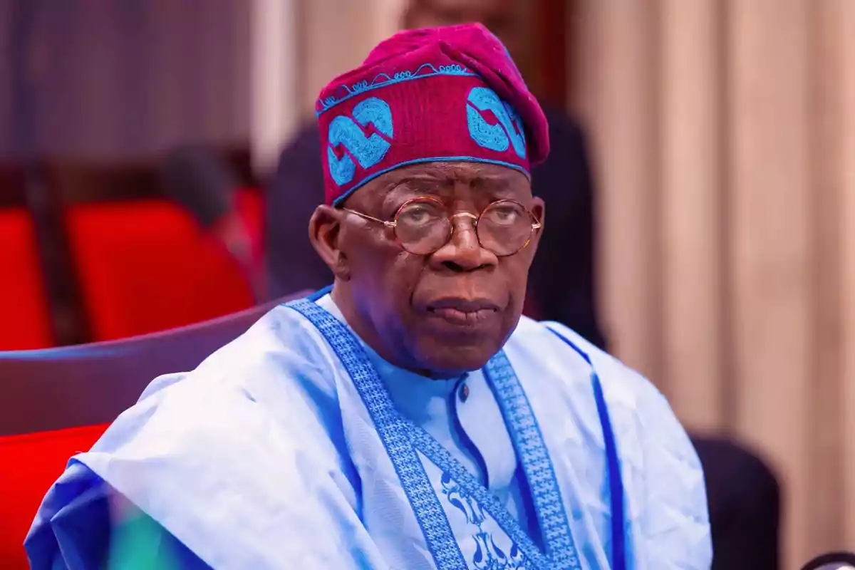 Elderly man with glasses and traditional blue African clothing and a purple cap sitting in a place with red chairs Elderly man with glasses and traditional blue African clothing and a purple cap sitting in a place with red chairs