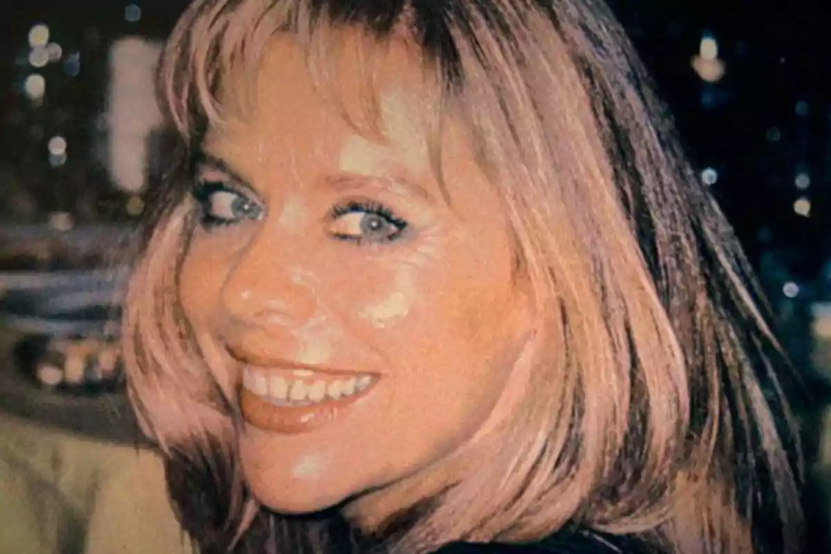 Blonde woman smiling and looking at the camera in a brightly lit indoor setting
