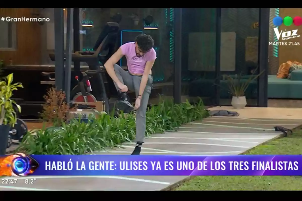 Person wearing a pink jersey and gray pants putting on a shoe in an indoor garden with plants and a treadmill in the background; on the screen, there is an announcement about a reality show finalist. Person wearing a pink jersey and gray pants putting on a shoe in an indoor garden with plants and a treadmill in the background; on the screen, there is an announcement about a reality show finalist.